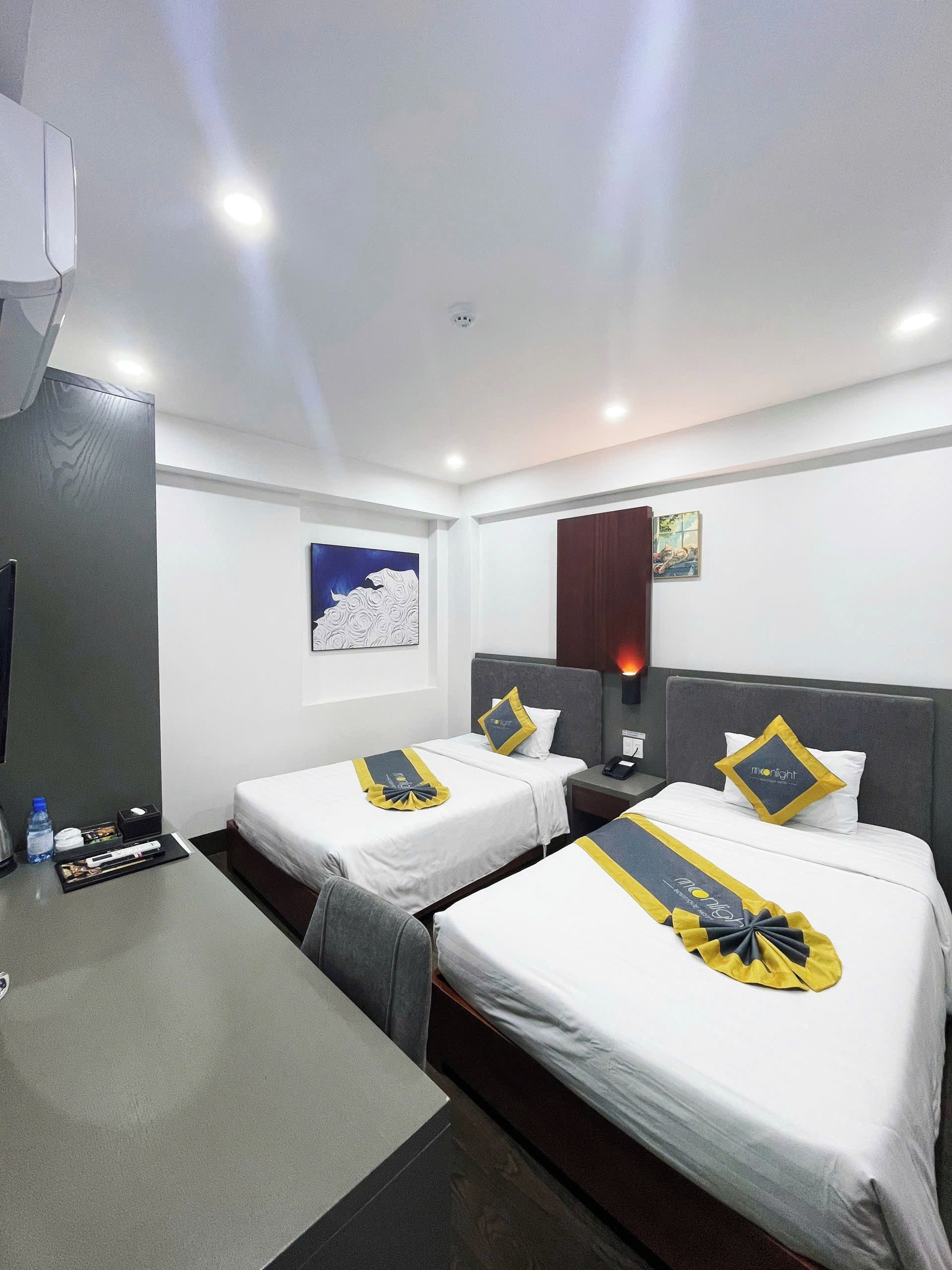 A hotel room with two single beds, a desk, and a nightstand with a phone.