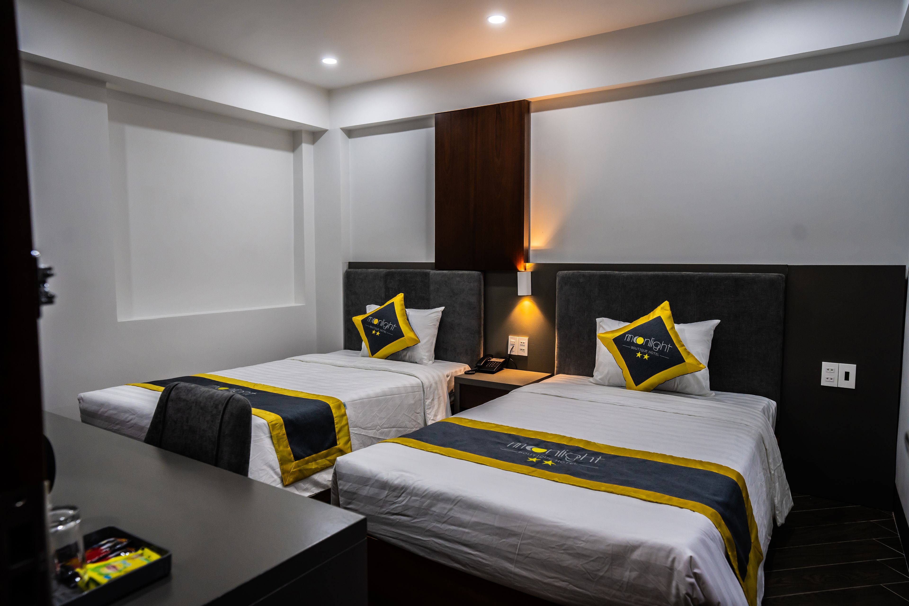 A hotel room with two beds, a desk, and a nightstand.