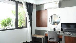 A hotel room with a desk, chair, TV, air conditioning unit, and a window with curtains. - Moonlight Boutique Hotel (Hue)