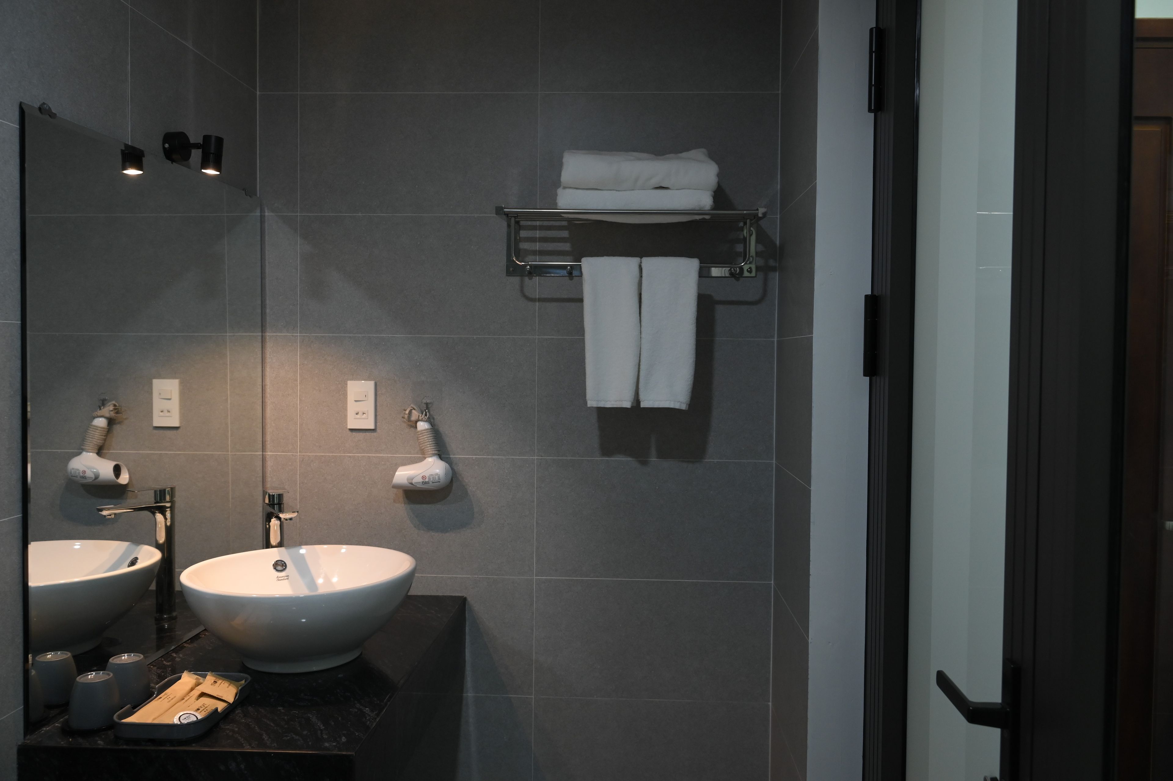 A modern bathroom with two sinks, a towel rack, and a hairdryer.