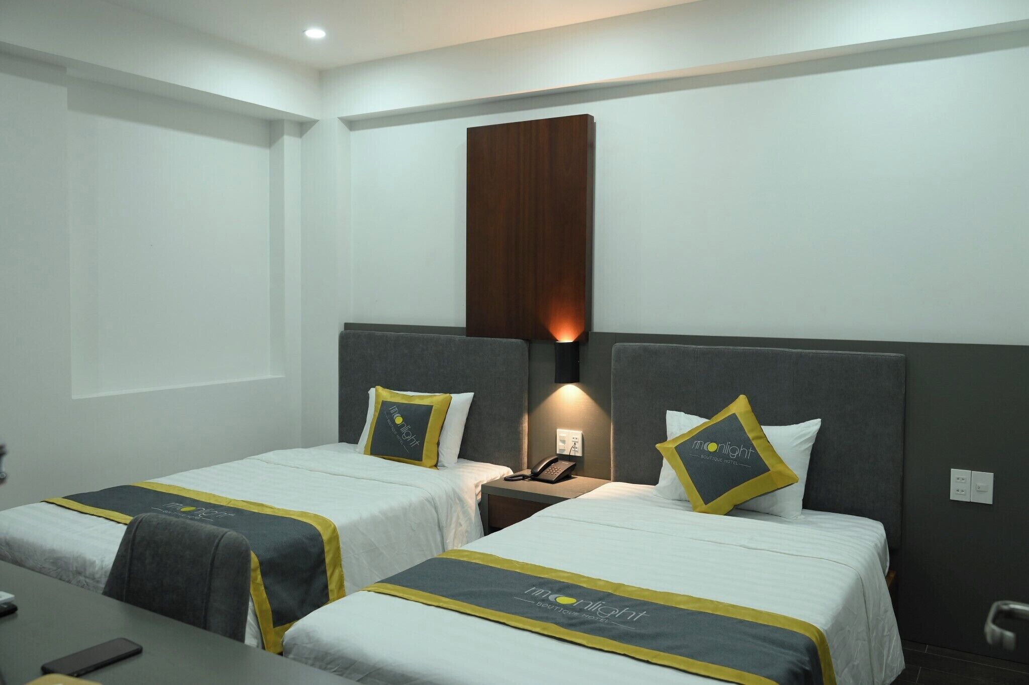 Una habitación de hotel con dos camas individuales, un escritorio y una mesita de noche con un teléfono.