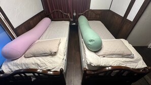 Une petite chambre, de taille modeste, avec deux lits simples, chacun étant équipé d’un oreiller et d’une couverture.