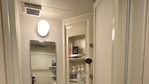 Une petite salle de bain compacte, équipée de toilettes, d’un lavabo et d’une douche.