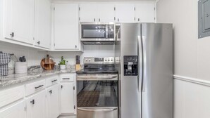 A modern kitchen with white cabinets, stainless steel appliances, and a granite countertop. - Camille Cottage ~ Ideal for Short-Term Stays or Traveling Professionals (Columbus)