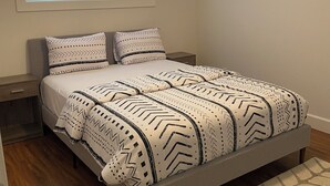 A bedroom with a bed, nightstands, a window with blinds, and a patterned rug. - Spacious 3-bedroom Suite in fabulous Surrey Wi-Fi, EV Charging, Basketball Court (Surrey)