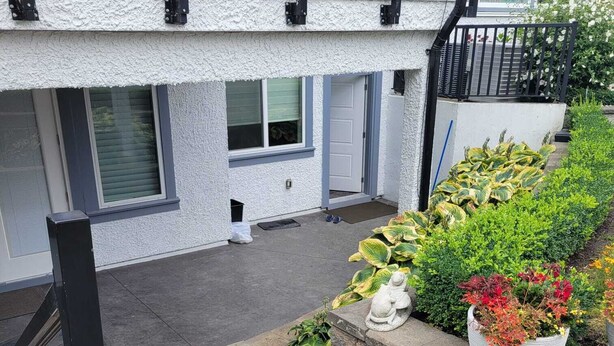 A residential building with a stone staircase leading to a front door, surrounded by potted plants and a statue. - Spacious 3-bedroom Suite in fabulous Surrey Wi-Fi, EV Charging, Basketball Court (Surrey)