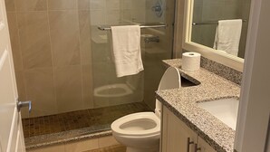 A modern bathroom with a glass-enclosed shower, a toilet, and a sink with a granite countertop. - Spacious 3-bedroom Suite in fabulous Surrey Wi-Fi, EV Charging, Basketball Court (Surrey)