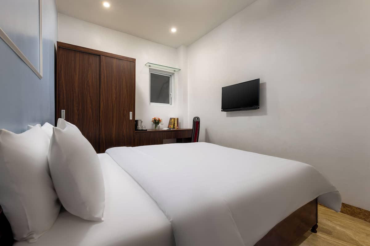 Une chambre à coucher avec un lit, une armoire, une télévision et une fenêtre.