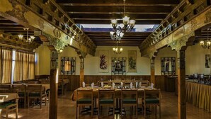 A dining hall with wooden tables and chairs, chandeliers, and ornate architectural details. - Lharimo North Cottage (Leh)