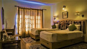 A room with two beds, a desk, a chair, and a window with curtains. - Lharimo North Cottage (Leh)