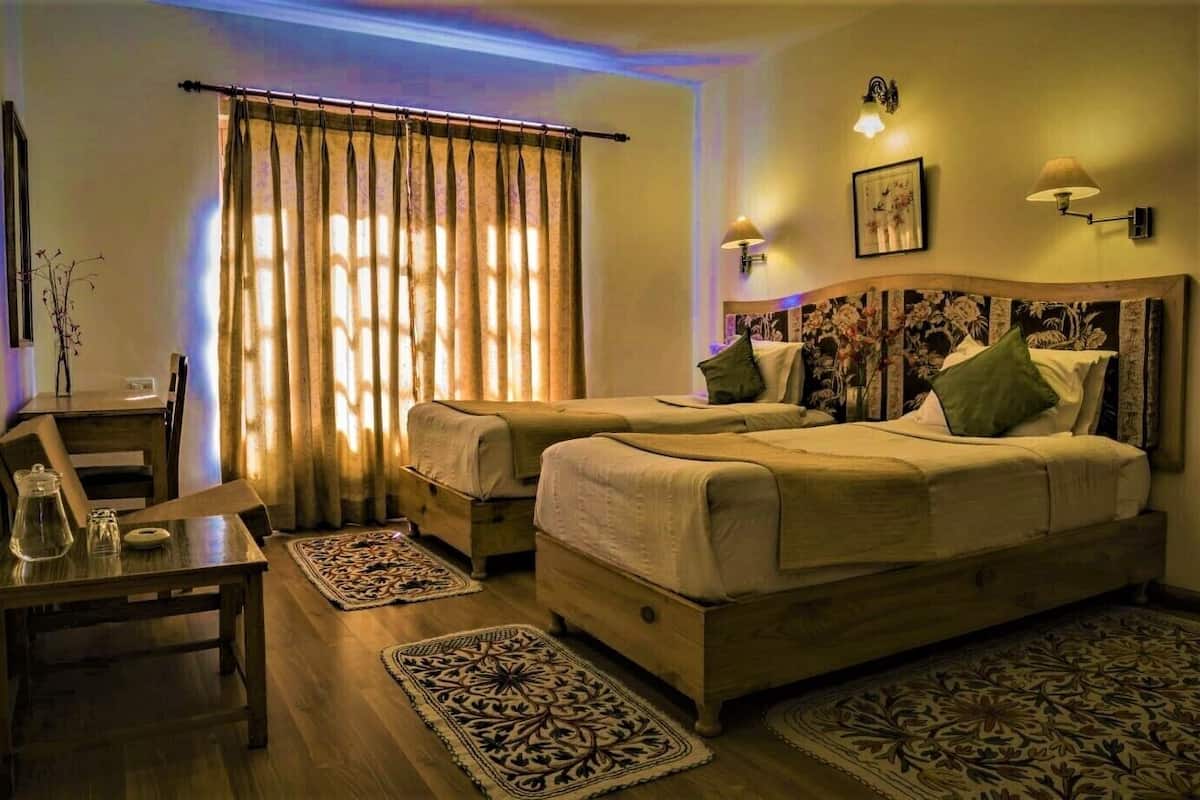 Una habitación con dos camas, un escritorio, una silla y una ventana con cortinas.