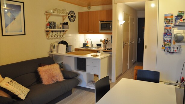 A compact living space with a kitchenette, a dining area, and a sofa with a decorative pillow. - Studio near the ski station, 4 ppl, balcony (Les Deux Alpes)