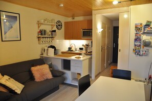 Um espaço compacto com cozinha compacta, área de refeições e sofá com almofada decorativa.