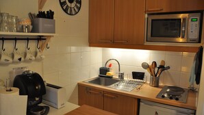 A kitchen with wooden cabinets, a stainless steel sink, a microwave, a coffee maker, and a dish rack. - Studio near the ski station, 4 ppl, balcony (Les Deux Alpes)