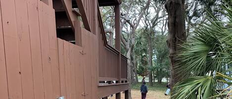 A wooden deck with a stone pathway leading to a park area.
