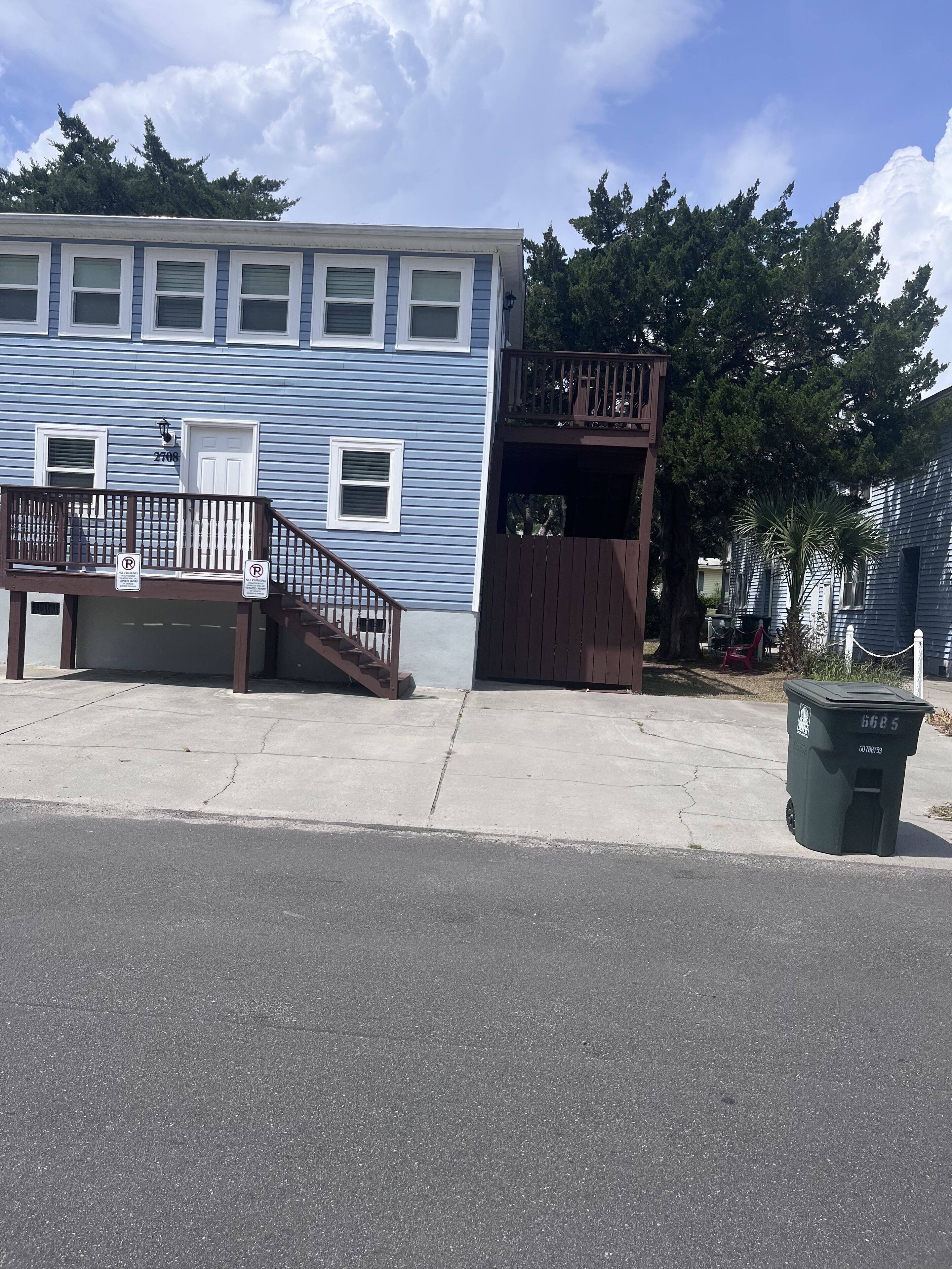 A residential building with a blue exterior, a front porch, and a garage.