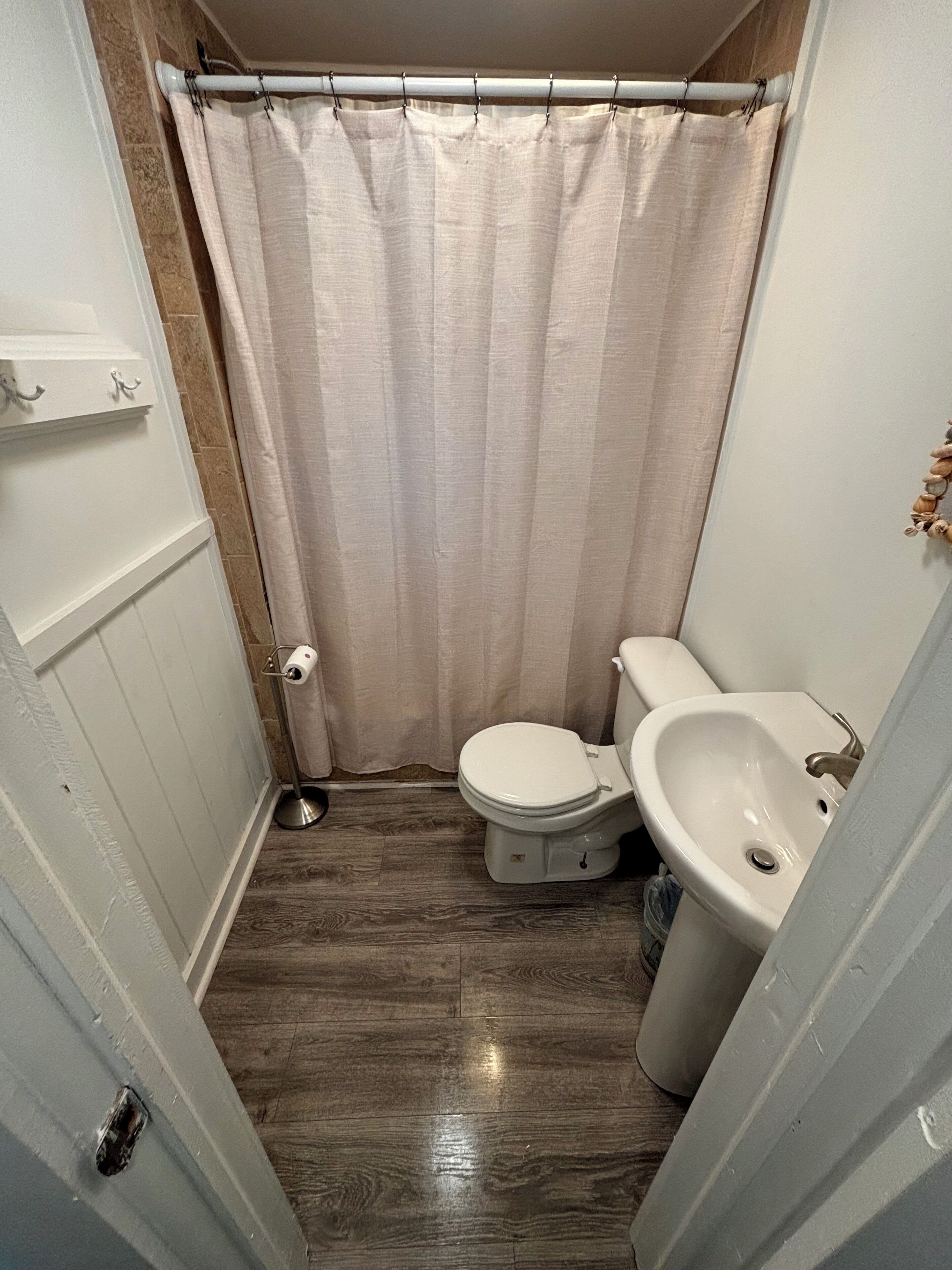 A small bathroom with a toilet, sink, and shower curtain.