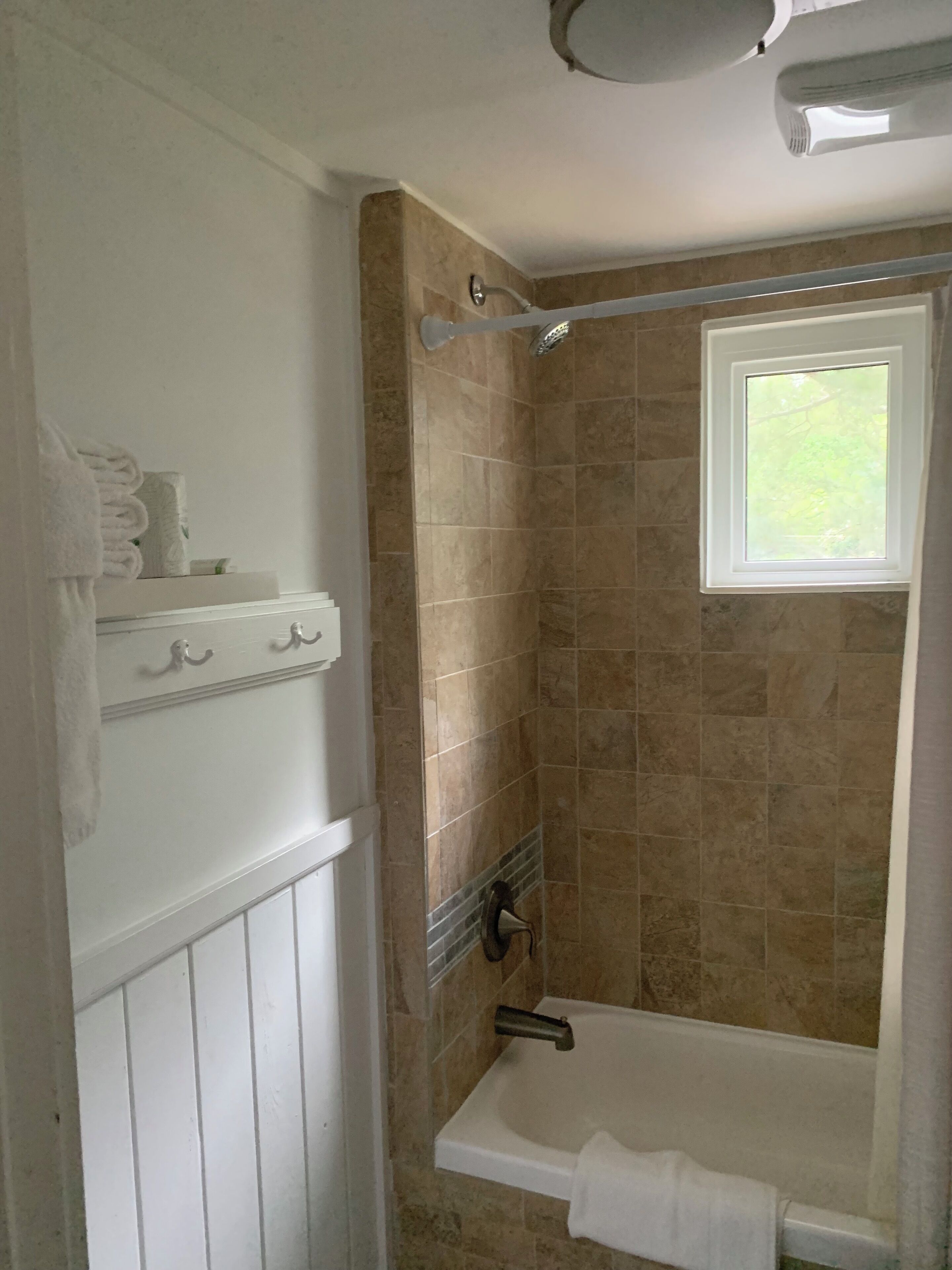A bathroom with a bathtub, a shower, and a window.