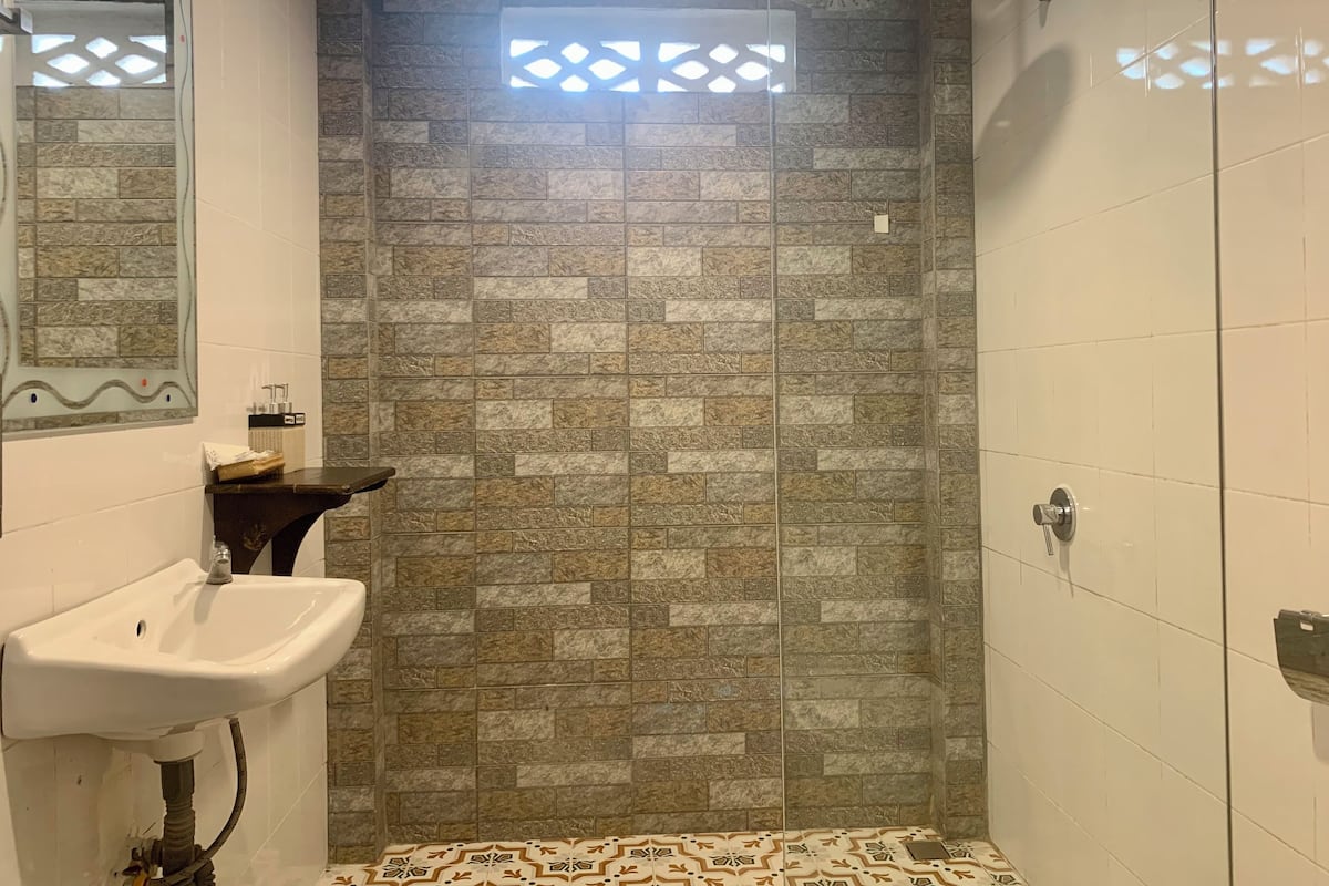 Een badkamer met een douche, wastafel en decoratieve wand.