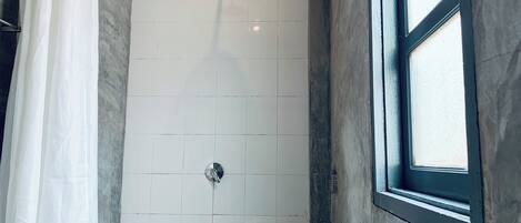 Un baño con ducha, lavamanos y ventana.