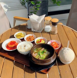 Une table en bois sur laquelle se trouvent divers plats, notamment un bol de riz, un bol de soupe et plusieurs petits bols contenant différents aliments.