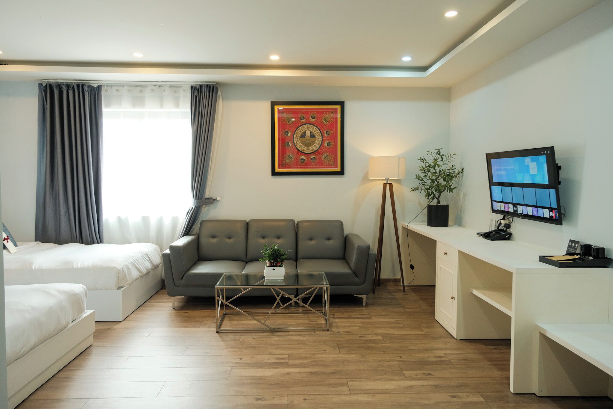 A modern living room with a sofa, a coffee table, a desk with a computer monitor, and a lamp.
