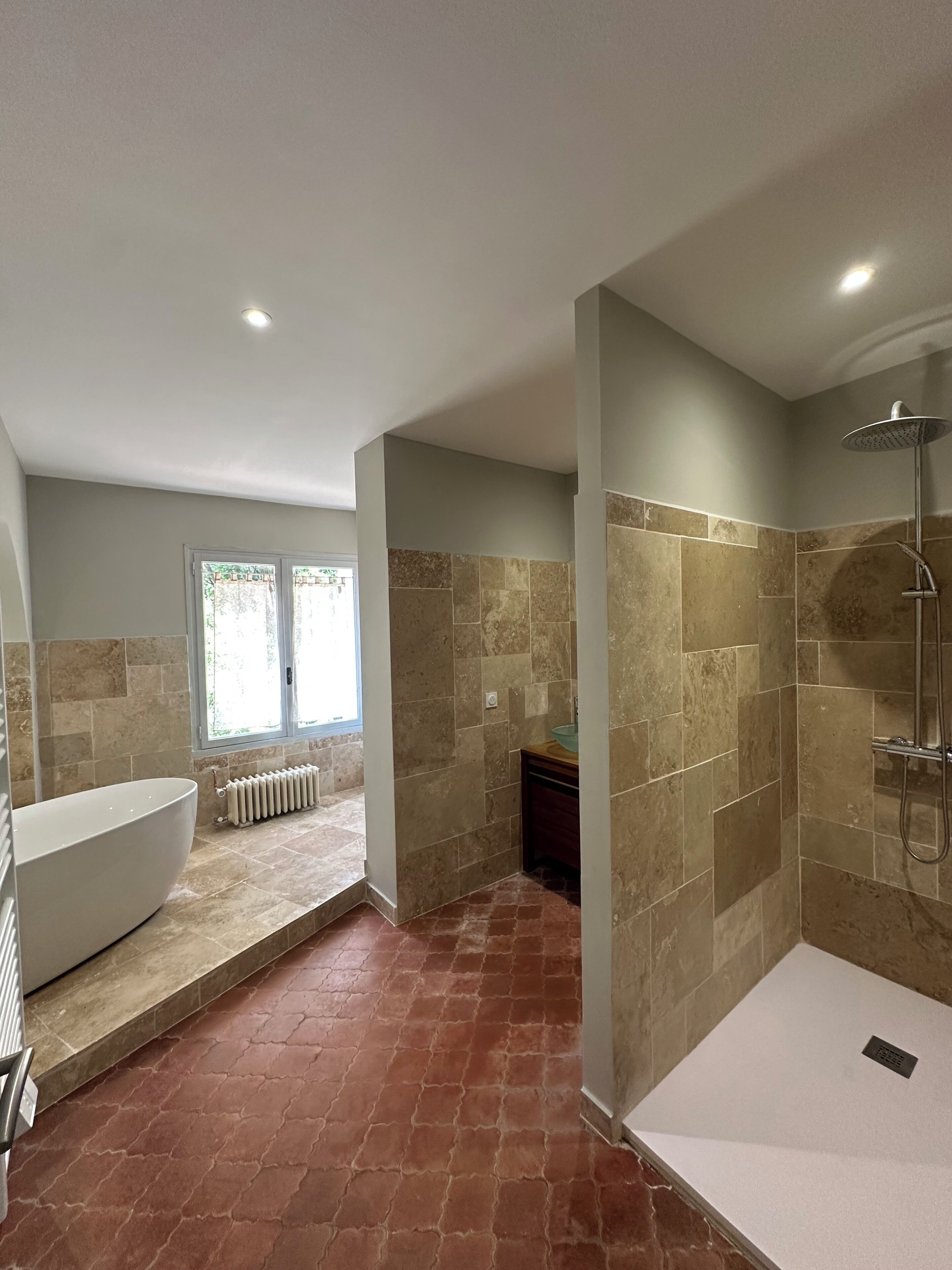 Ein modernes Badezimmer mit Badewanne, Dusche und Fenster.
