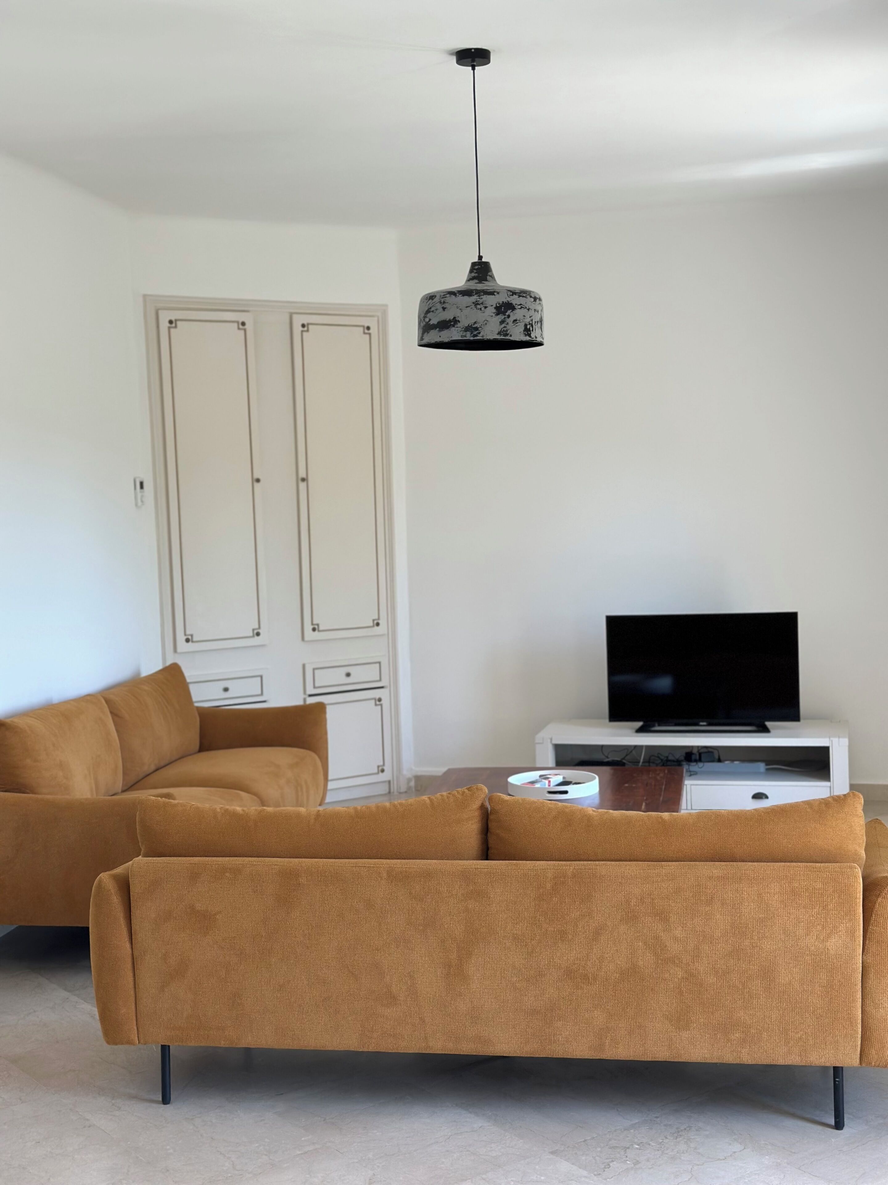 Een woonkamer met een bank, televisie en een kast.