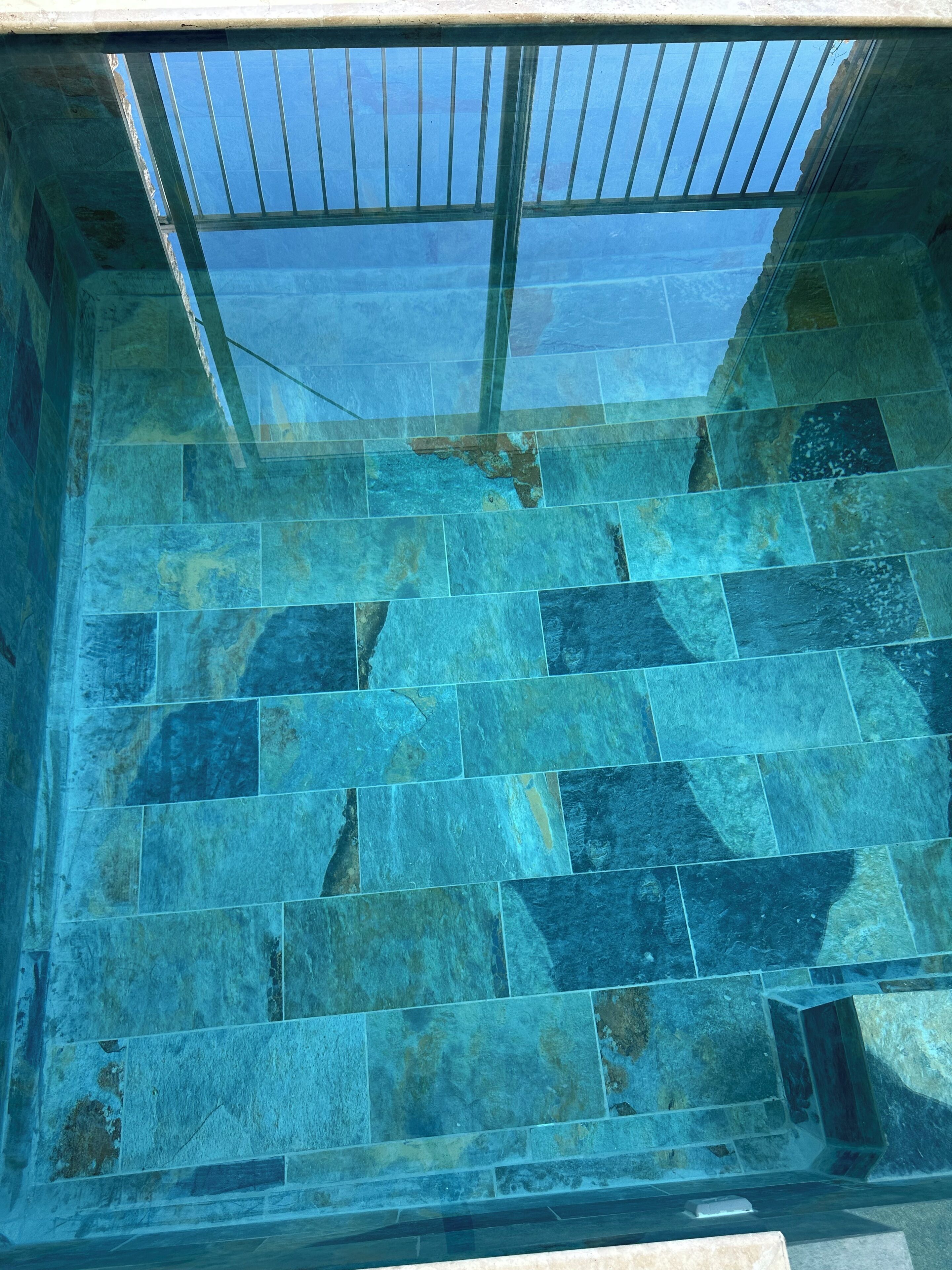 Ein Pool mit Glasabdeckung und Steinfliesen.