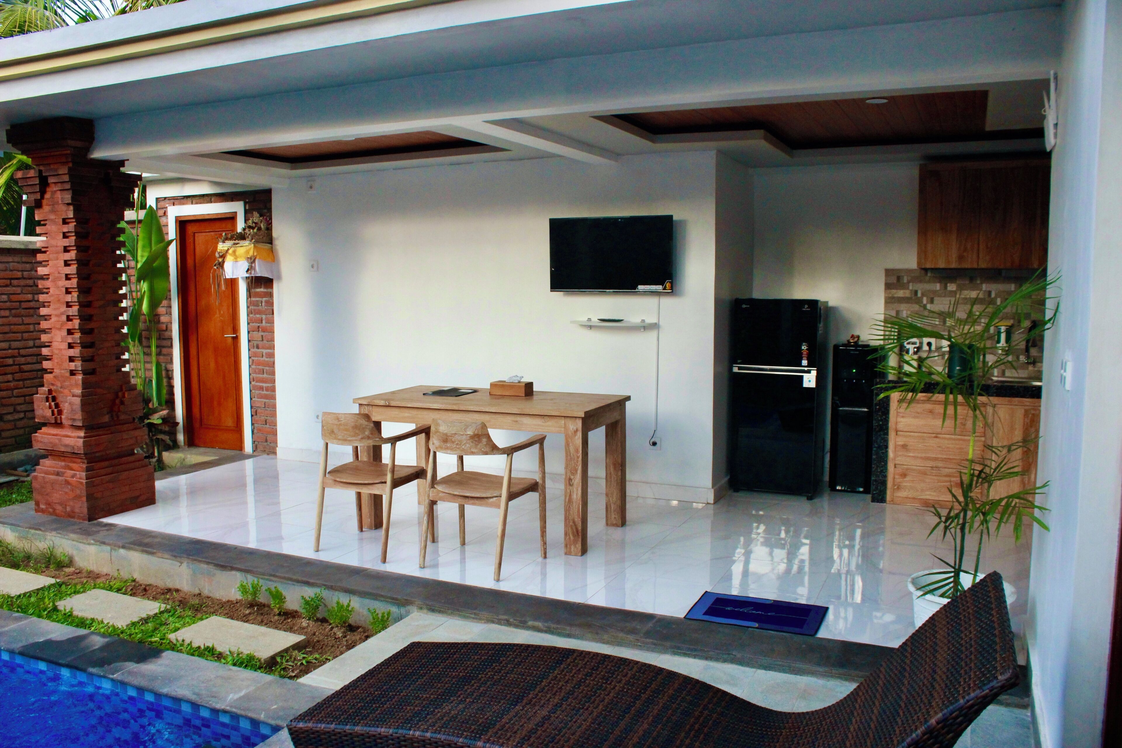 Un área de comedor exterior moderna con un pilar de ladrillo, una mesa de madera y sillas.