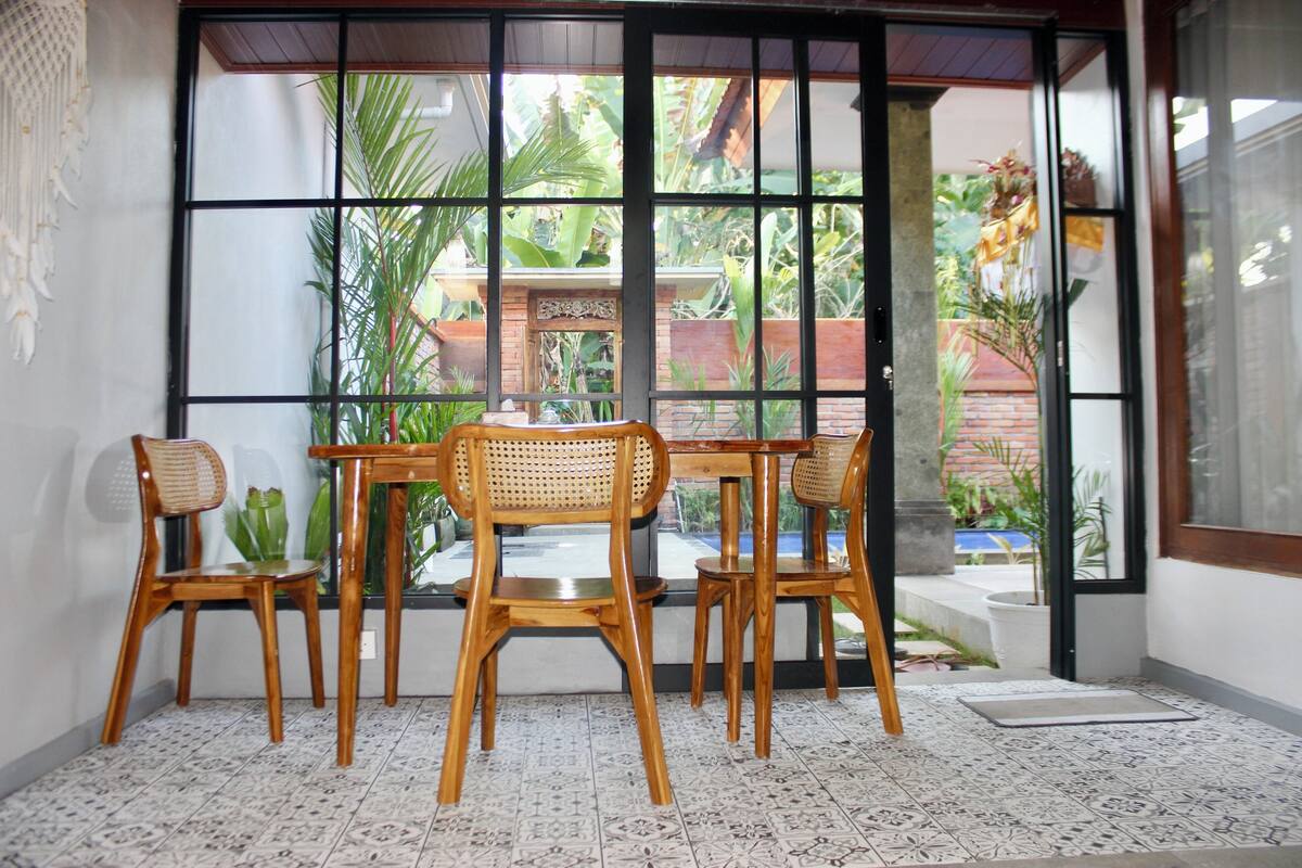 A room with a large window, a wooden table, and four chairs.