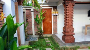 A well-maintained garden with a brick pathway leading to a wooden door, surrounded by lush greenery and a stone bench. - Ubud Arindra Private Pool Villa (Ubud)