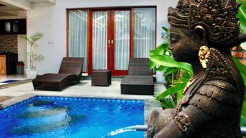 A statue by a swimming pool with a sliding glass door in the background.