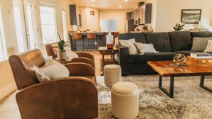 A modern living room with a dark sofa, leather armchairs, and a wooden coffee table. - Panoramic Lookout *Sierra Serenity* BBQ by CasaOso (Mariposa)