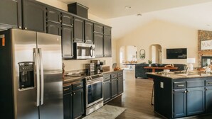 A modern kitchen with dark cabinetry, stainless steel appliances, and a central island. - Panoramic Lookout *Sierra Serenity* BBQ by CasaOso (Mariposa)