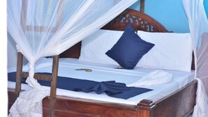 A bed with a wooden headboard, white bedding, and a blue pillow. - La Neisha hotel Nungwi (Nungwi)
