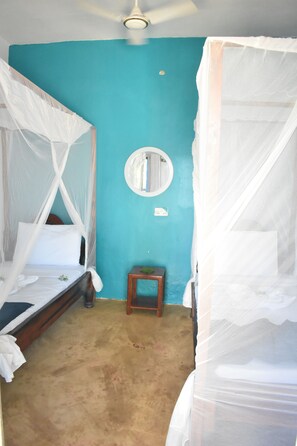 A room with two beds, each with a canopy, a small wooden stool, and a round mirror on the wall. - La Neisha hotel Nungwi (Nungwi)