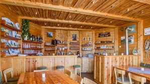 Un intérieur en bois comprenant un bar, des sièges et des étagères où sont exposés divers objets.