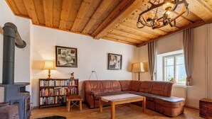 Un salon chaleureux avec un plafond en bois, une cheminée, un canapé en cuir, une table basse en bois et une bibliothèque.