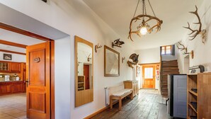Un hall d’entrée spacieux, doté d’un plancher en bois, d’un banc en bois, d’un miroir et de décorations en forme de bois de cerf sur les murs.