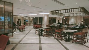 Un espaiós restaurant amb un sostre alt, diverses taules de dinar i una zona de bar central.
