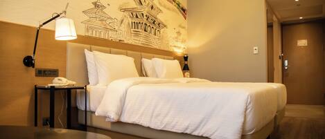 A hotel room with a bed, bedside lamp, and a wall mural.