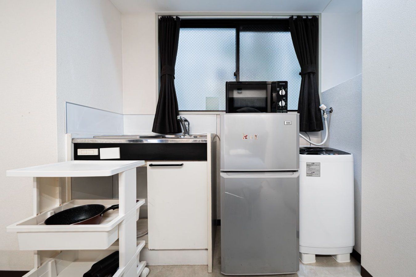 A compact kitchen with a refrigerator, microwave, and a small water dispenser.