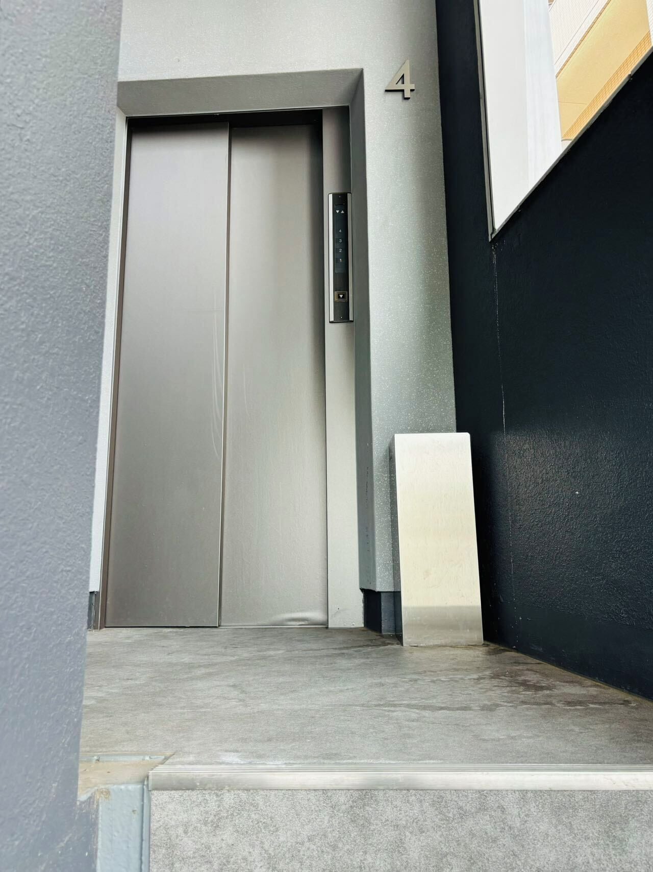 En moderne elevator med metalfinish, digitalt kontrolpanel og dør med håndtag.