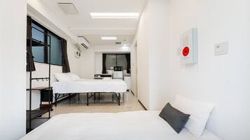 A hotel room with two beds, a desk, a chair, a microwave, and a red emergency alarm.
