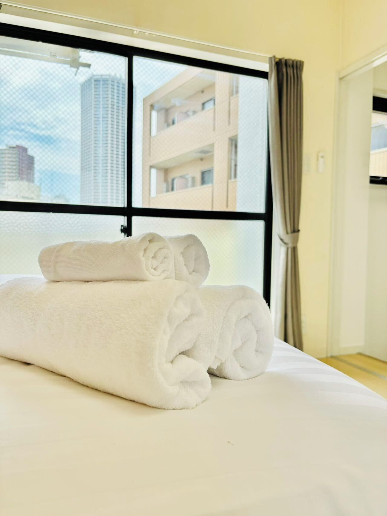Une chambre d’hôtel avec un lit, une fenêtre donnant sur le paysage urbain et un rideau.