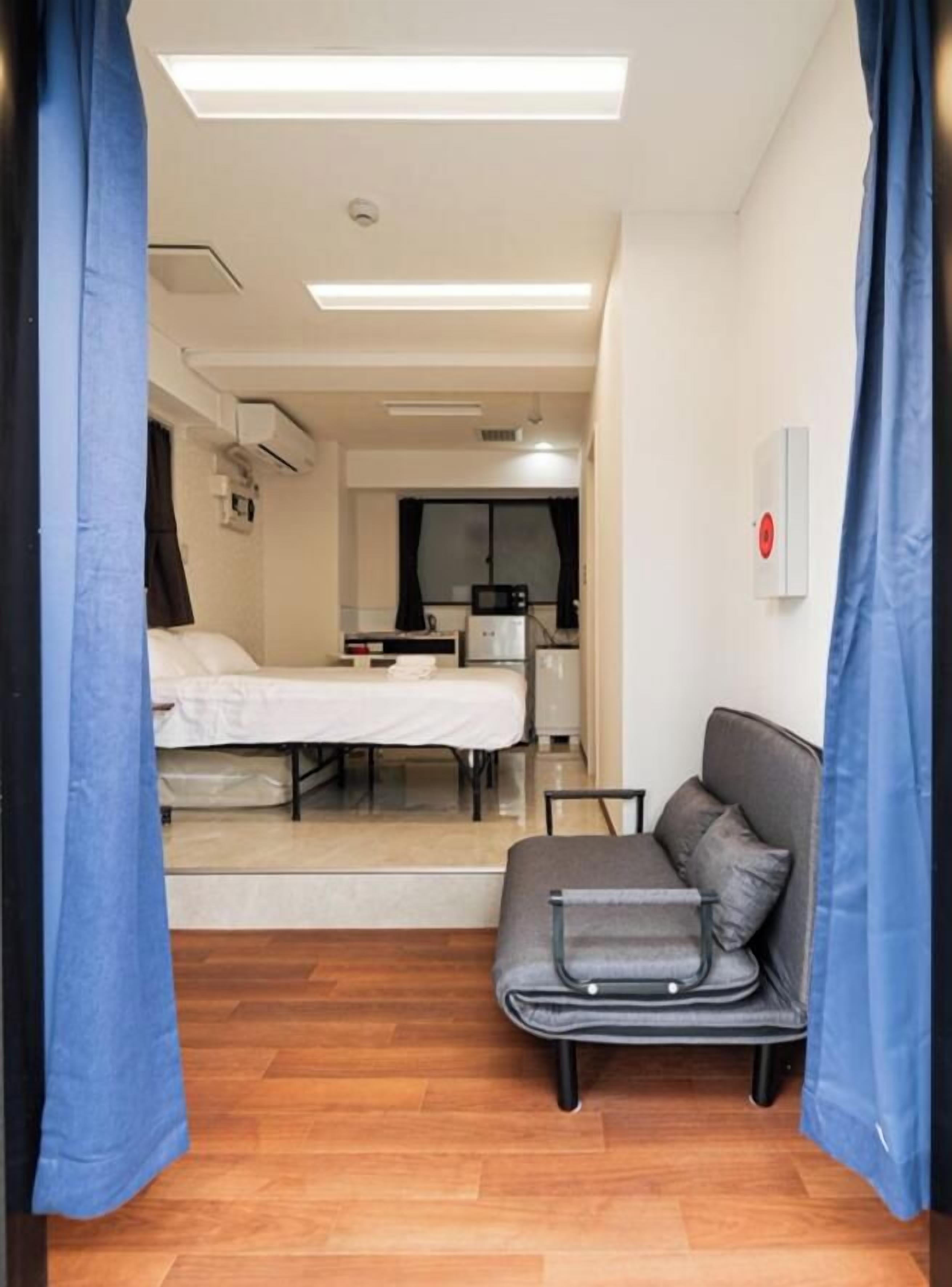 A hotel room with a bed, a sofa, a desk, and a kitchenette.