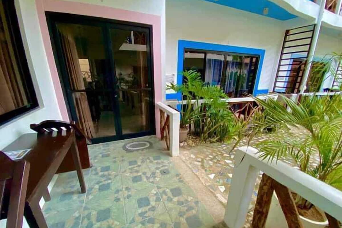 A tiled patio with a table and chairs, a door, and potted plants.