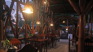 Un espace de restauration intérieur avec des tables et des chaises en bois, des lampes suspendues et un sol à motifs.
