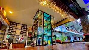 Un hall d’entrée spacieux avec un comptoir d’accueil en bois, une vitrine et un lustre moderne.